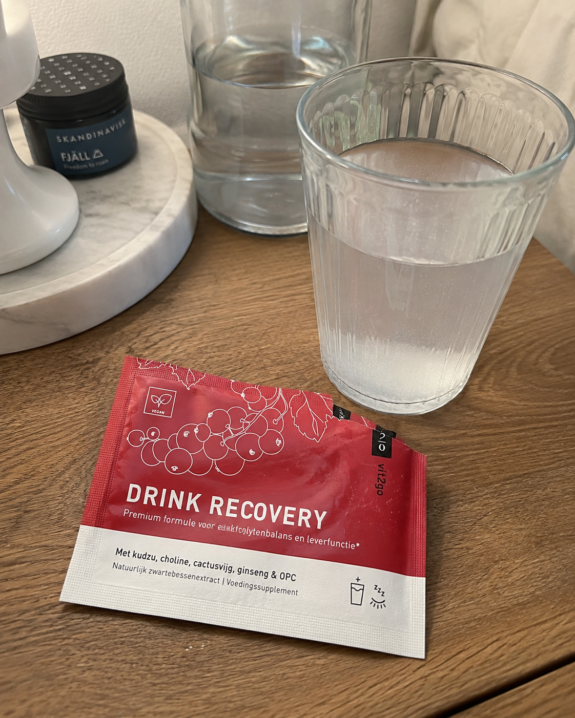Vit2go Drink Recovery on the nightstand with a glass of water